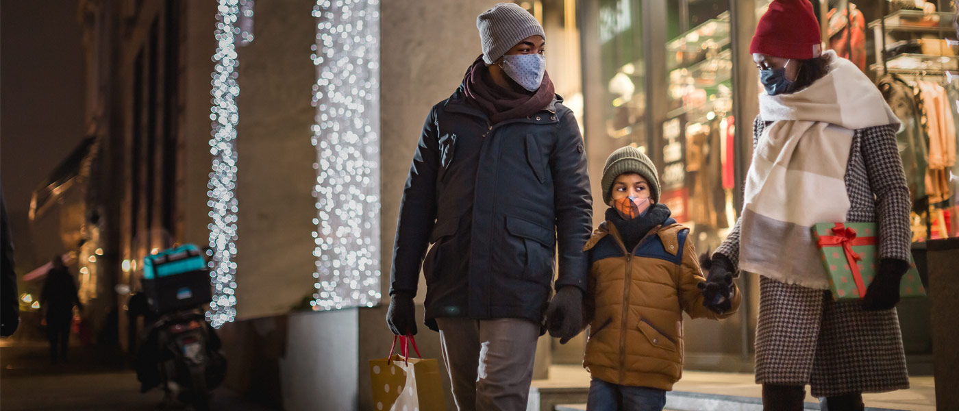 图为穿着冬装、戴着口罩的父母和孩子手牵着手离开商店