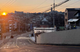 这张照片俯瞰着韩国首尔一条几乎空无一人的道路，背景是建筑物，夕阳西下
