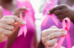 图为妇女高举粉红色的乳腺癌宣传丝带