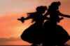 前两个夏威夷草裙舞舞者优雅地移动热带夕阳温暖的光亮。图像所提供的盖蒂图片社