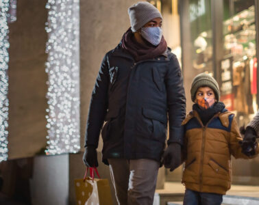 父母和一个孩子握手的照片当他们离开冬天衣裳和面具的商店。