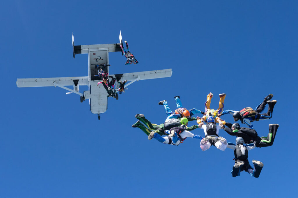 一群跳伞运动员从飞机上跳下来并形成队形的照片