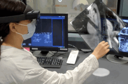一名戴着混合现实耳机的女性正在电脑屏幕上观看核磁共振成像中的病人