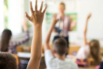 教室里的学生照片，其中一名学生明显地举起了一只手