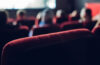 从电影院座位后面拍摄的照片，其中一些座位上有模糊的人